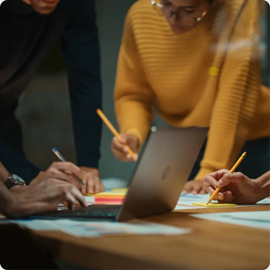 A team reviewing documents around a laptop